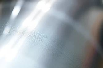 A close-up shot showcasing a futuristic, highly durable coating applied to a metallic surface. The coating should have a subtle, textured appearance, suggesting resilience and longevity. Focus on the surface detail and the way light reflects off the coating. The background should be blurred, emphasizing the coating itself.