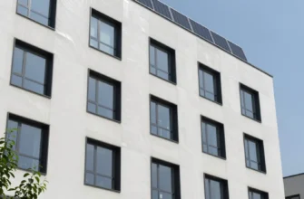 A modern building with advanced thermal insulation visible on its exterior. The insulation should be depicted as a layer integrated into the building's facade, showcasing its technological aspects. Include subtle visual cues representing energy efficiency, such as solar panels or green walls. The overall scene should convey innovation and sustainability.